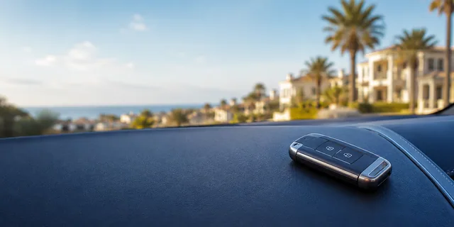 Car key fob on a navy dashboard with Mediterranean surroundings softly blurred